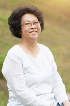 Happy Asian mature woman relaxing at outdoor park.