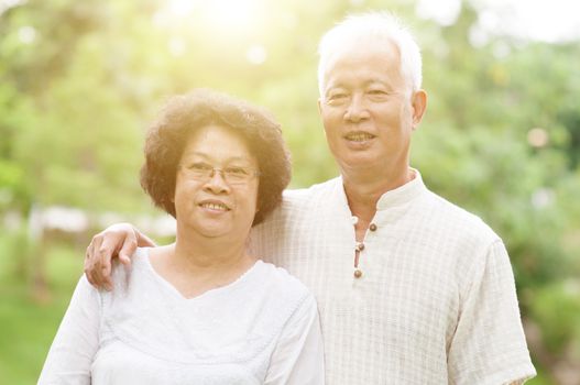 Happy Asian elderly couple smiling at outdoor park on a sunny day.