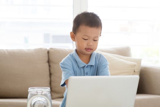 Asian boy using computer laptop at home. Child education and technology concept. 