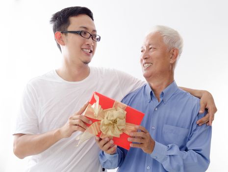 Asian elderly father and son hand holding a gift box and smiling,  standing isolated on white background.