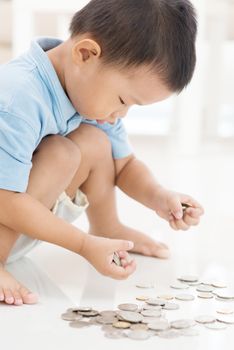 Asian boy saving money at home. Child education fund concept. 