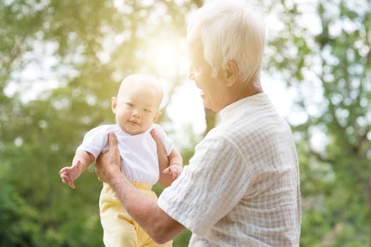 Grandfather taking care of baby grandchild in outdoor park. Asian family, life insurance concept.