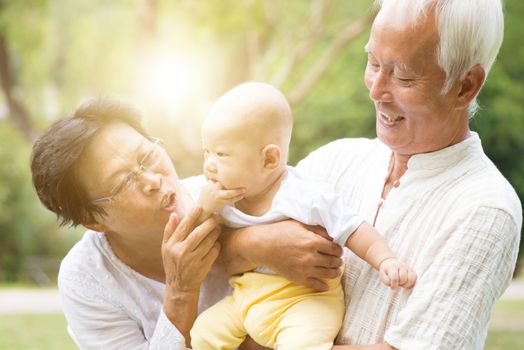 Grandparents taking care of grandchild in outdoor park. Asian family, life insurance concept.