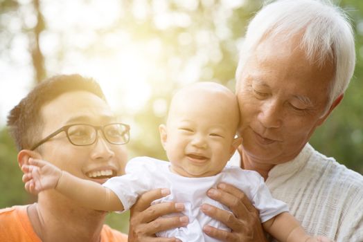 Baby grandchild, father and grandfather. Asian multi generations family having fun outdoors. Life insurance concept.