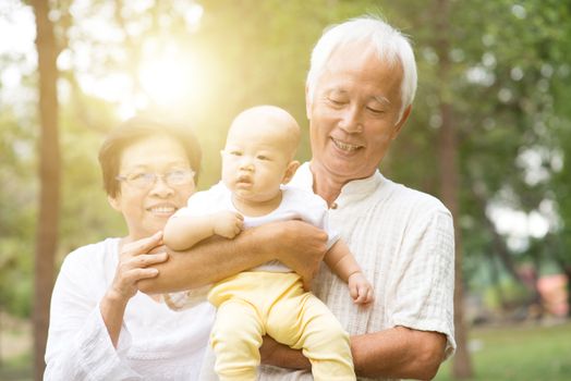 Happy grandparents with cute grandson at outdoors park. Asian family, life insurance concept.