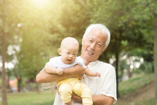 Grandfather with baby grandson at outdoor park, Asian family.