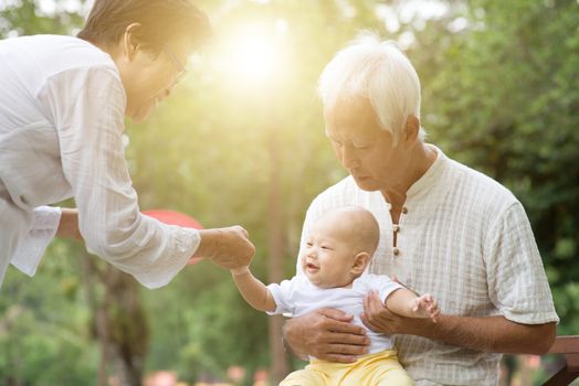 Baby grandson and grandparents having fun outdoors. Asian family, life insurance concept.