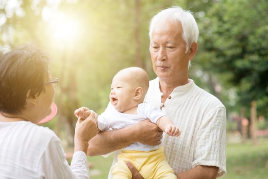 Happy grandparents with baby grandchild at outdoors park. Asian family, life insurance concept.