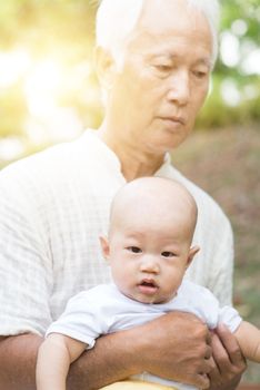 Grandfather taking care of baby grandson in outdoor park. Asian family, life insurance concept.
