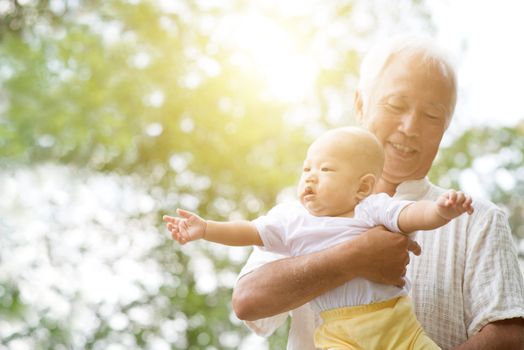 Happy grandfather playing with grandson at outdoor park, Asian family.