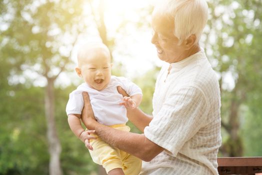 Baby grandchild and grandfather having fun outdoors. Asian family.