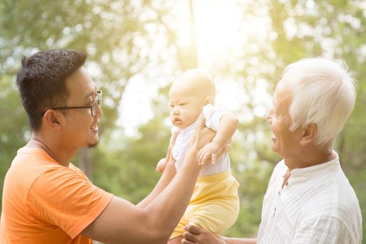 Happy grandfather, father and baby grandchild at outdoors park. Asian multi generations family.