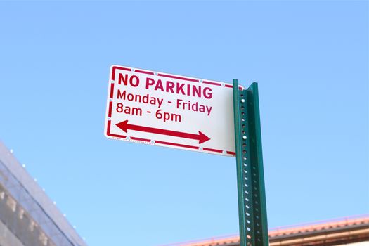 NO PARKING street sign, applicable daytime on week days, stands against a blue sky