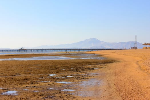 Low tide on the beach. Sanny shote and blue mountains