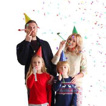 Family blowing party trumpets with confetti celebrating new year