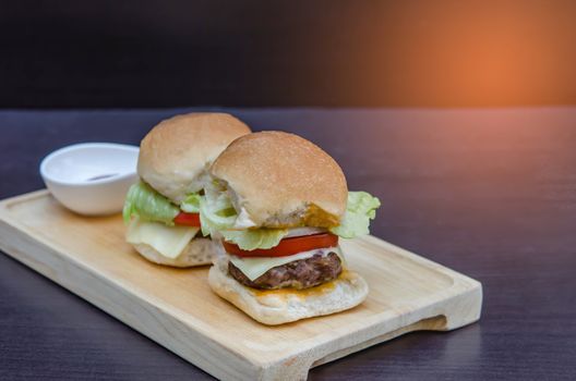 Delicious homemade gourmet cheese burgers made from beef with fresh ingredients placed on wooden platters