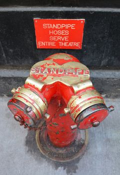 Red and gold siamese standpipe outside a Broadway theatre - firefighting water connection