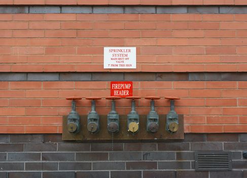 Six firepump test headers on red brick wall, for testing the flow capacity of fire pumps