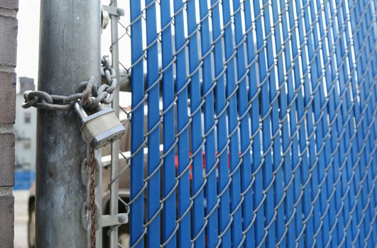 Heavy-duty padlock and chain locking security gate made of metal chainlink and blue plastic