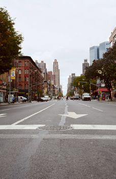 NEW YORK - OCTOBER 23, 2017: 9th Avenue crosswalk, looking north east up the street. Selective focus on manhole cover in road, with Manhattan buildings, traffic and pedestrians beyond.