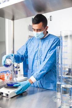 Young male scientist working with an stirrer at laboratory dressed in blue