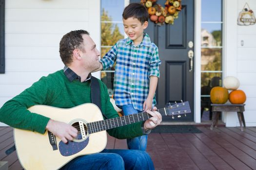 Young Mixed Race Chinese and Caucasian Son Singing Songs and Playing Guitar with Father