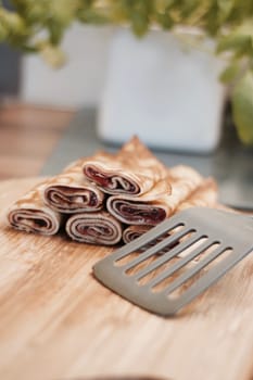 Delicious and fresh pancakes with strawberry sauce on the wooden board in the kitchen.