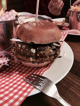 Big, fresh and delicious vegetable burger in restaurant on the white plate.