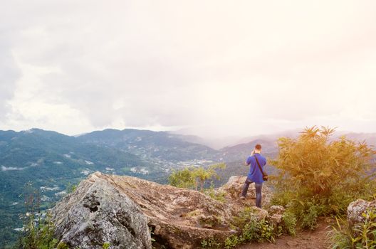 Young traveler standing on the mountains looks into the sunset.