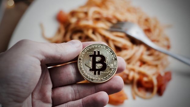 Digital currency physical metal bitcoin coin. Restaurant pasta concept.