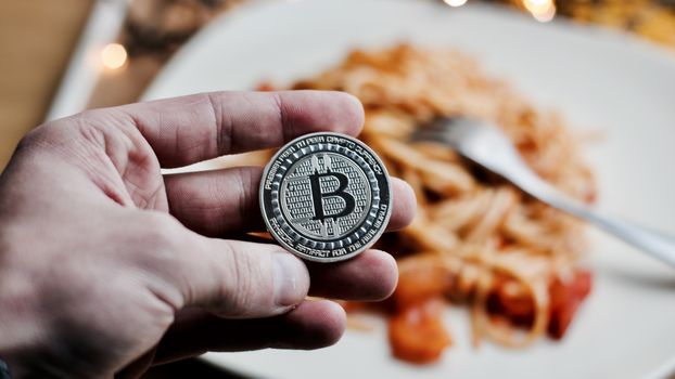 Digital currency physical metal bitcoin coin. Restaurant pasta concept.