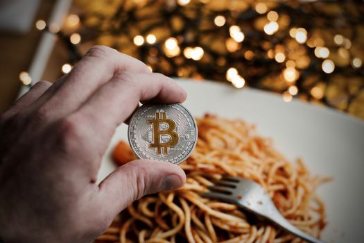 Digital currency physical metal bitcoin coin. Restaurant pasta concept.