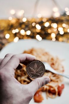 Brass marijuana coin with leaf. Italian pasta food concept.