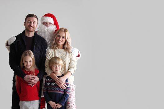 Portrait of young family with two children with Santa Claus, gray background with copy space for text