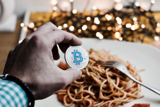 Digital currency physical metal bitcoin coin. Restaurant pasta concept.