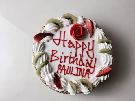 Tasty cake with happy birthday paulina inscription. Cake with strawberry and kiwi.