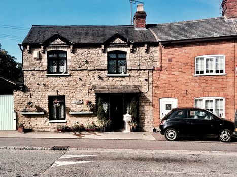 Old house and small black car near the road. Brick wall building.