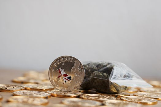 Europe leaving. Silver brexit coin with british map near bag with marijuana.