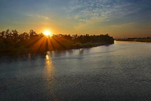 Aerial image showing a sunrise over the water with sunbeams. Beautiful landscape with river and bright sun rays