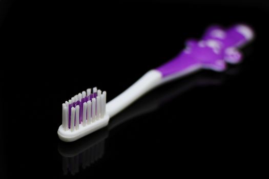 toothbrush for a child reflected on a black background
