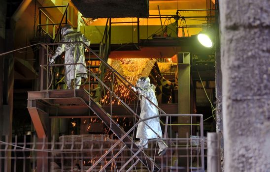 Molten Metal Pouring Out Of Furnace and Workers