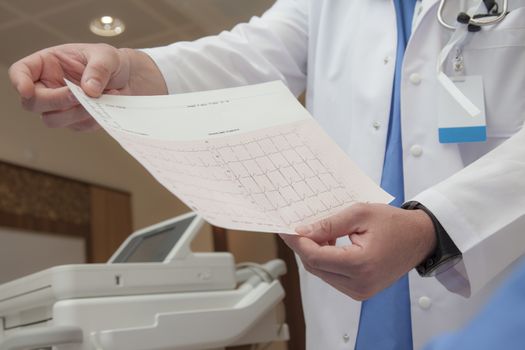 A doctors hand are holding a graph with an unconfirmed diagnosis of normal heart rate.