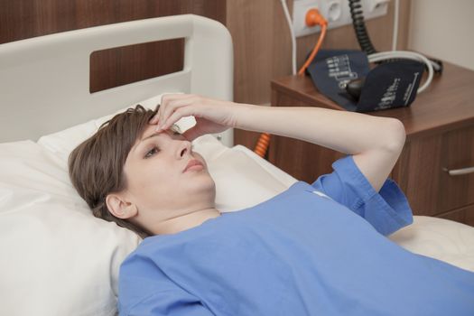 A young female patient lying in hospital with a headache