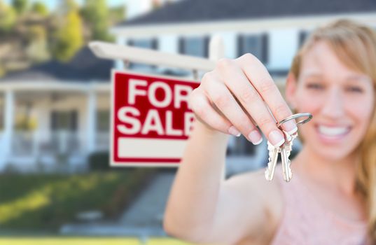 Excited Woman Holding House Keys and For Sale Real Estate Sign in Front of Nice New Home.