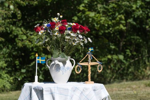 Table decorated with flowers and miniatures for midsummer celebration outdoors in a garden
