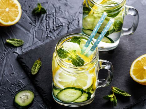 Detox water with cucumber, lemon and mint. Summer drink in mason jar on dark concrete background . Copy space