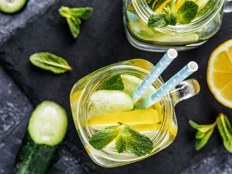 Above view of two mason jar with detox water on dark concrete background. Summer drink with cucumber, lemon and mint. Copy space. Top view or flat lay