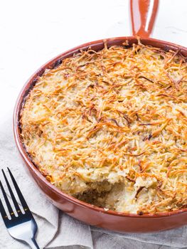 Close up view of appetizing potato casserole with fish, eggs and cream. Potato casserole in serving baking pan on white concrete background