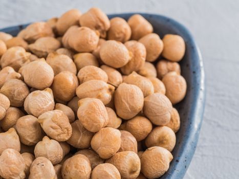 Extreme close up view of raw chickpea in plate on gray concrete background