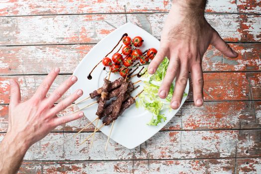 Arrosticini meat in a dish with salad and tomatoes on the table